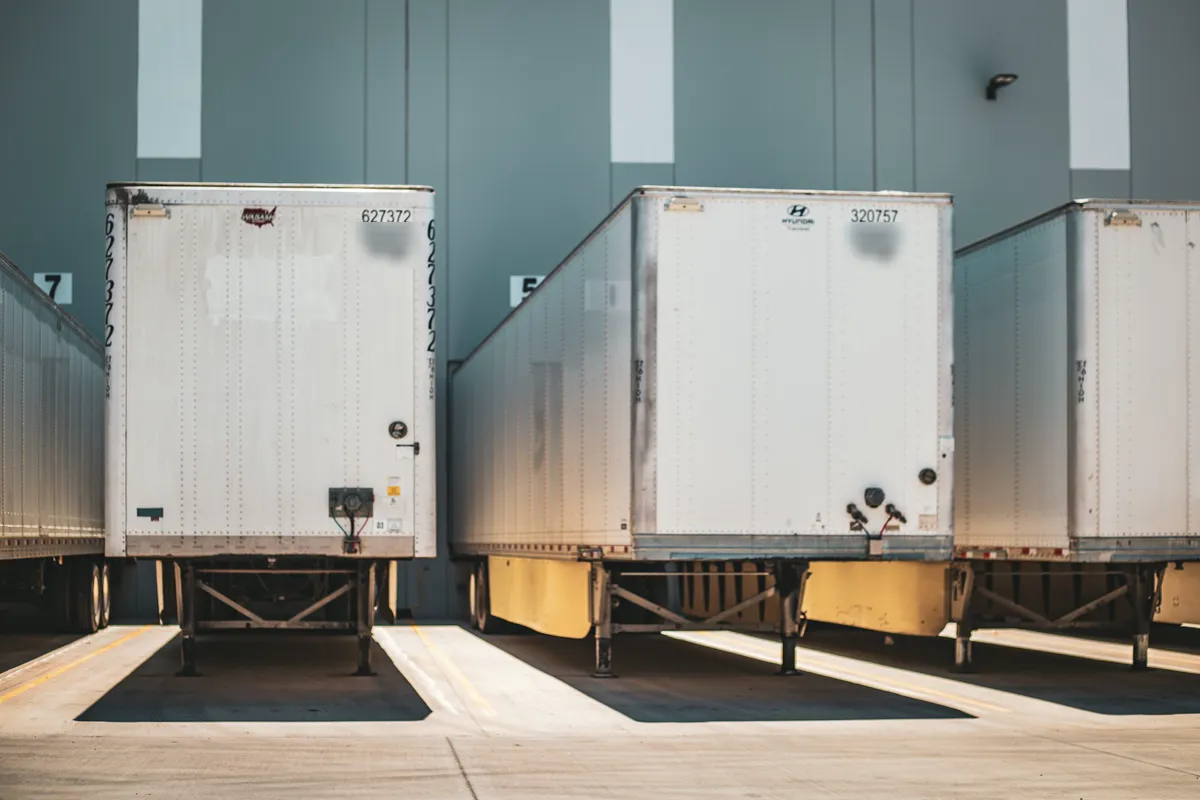 Row of dry van trailers backed into warehouse loading docks